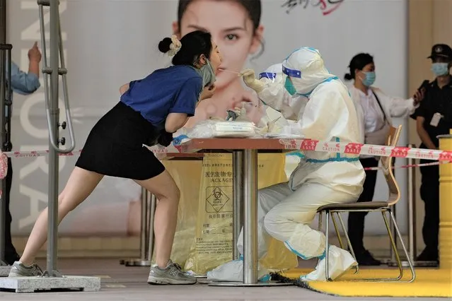 A woman gets a throat swab during a public COVID testing outside a shopping mall on Sunday, May 22, 2022, in Beijing. (Photo by Andy Wong/AP Photo)
