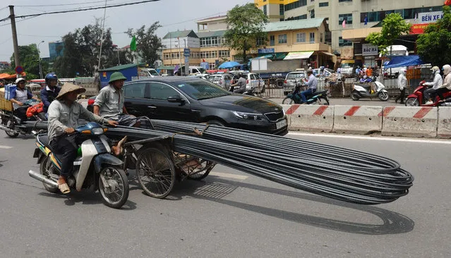 A man, helped by an other one riding a motorcycle, transports steel rods on a rickshaw as he makes way to deliver them to a construction site in Hanoi on June 8, 2016. (Photo by Hoang Dinh Nam/AFP Photo)