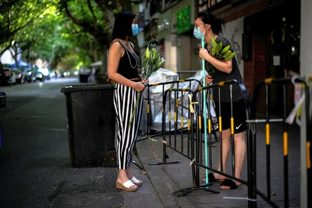 A resident gets flowers from her friend in a residential area, after the lockdown placed to curb the coronavirus disease (COVID-19) outbreak was lifted in Shanghai, China on June 8, 2022. (Photo by Aly Song/Reuters)