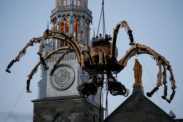 The giant mechanical spider Kumo, created by French production company La Machine, is lowered in front of the Notre-Dame Cathedral Basilica during a performance in Ottawa, Ontario, Canada, July 27, 2017. (Photo by Chris Wattie/Reuters)