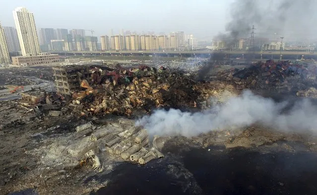 An aerial picture shows smoke rising from the debris among shipping containers at the site of Wednesday night's explosions at Binhai new district in Tianjin, China, August 15, 2015. (Photo by Reuters/Stringer)