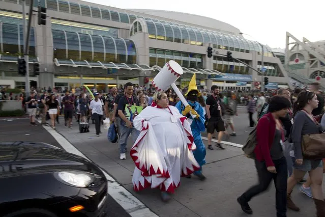 People cross the street during Comic-Con Thursday, July 24, 2014, in San Diego. Thousands of fans with four-day passes to the sold-out pop-culture spectacular flocked to the event Thursday, many clad in costumes. (Photo by AP Photo)