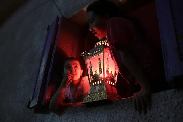 Egyptian children hold a traditional Ramadan lantern placed in a windowsill during the holy month of Ramadan in Cairo, Egypt, Friday, July 10, 2015. (AP Photo/Amr Nabil)