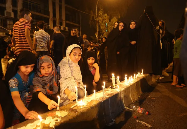 People light candles at the scene of a massive car bomb attack in Karada, a busy shopping district where people were shopping for the upcoming Eid al-Fitr holiday, in the center of Baghdad, Iraq, Monday, July 4, 2016. (Photo by Hadi Mizban/AP Photo)