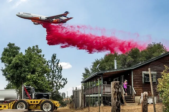 Karyn Larson watches an air tanker drop retardant as the Electra Fire burns towards her home in the Pine Acres community of Amador County, Calif., on Tuesday, July 5, 2022. (Photo by Noah Berger/AP Photo)
