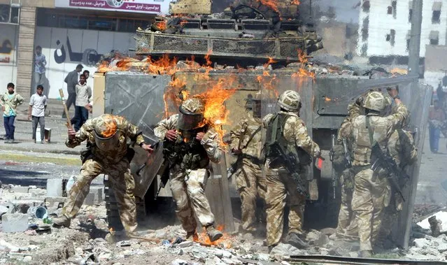 British Army troops are covered in flames from a petrol bomb thrown during a violent protest by job seekers, who say they were promised employment in the security services, in the southern Iraq city of Basra, Iraq March 22, 2004. (Photo by Atef Hassan/Reuters)