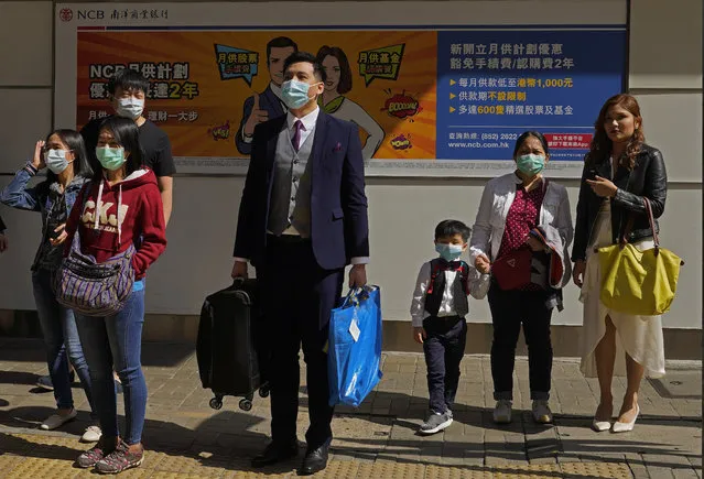 People wearing face masks wait at a pedestrian cross walk Hong Kong Saturday, February 22, 2020. COVID-19 viral illness has sickened tens of thousands of people in China since December. (Photo by Vincent Yu/AP Photo)