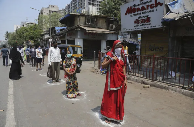Indians stand in marked positions to buy essential commodities from a grocery store in Mumbai, India, Wednesday, March 25, 2020.The world's largest democracy went under the world's biggest lockdown Wednesday, with India's 1.3 billion people ordered to stay home in a bid to stop the coronavirus pandemic from spreading and overwhelming its fragile health care system as it has done elsewhere. (Photo by Rafiq Maqbool/AP Photo)
