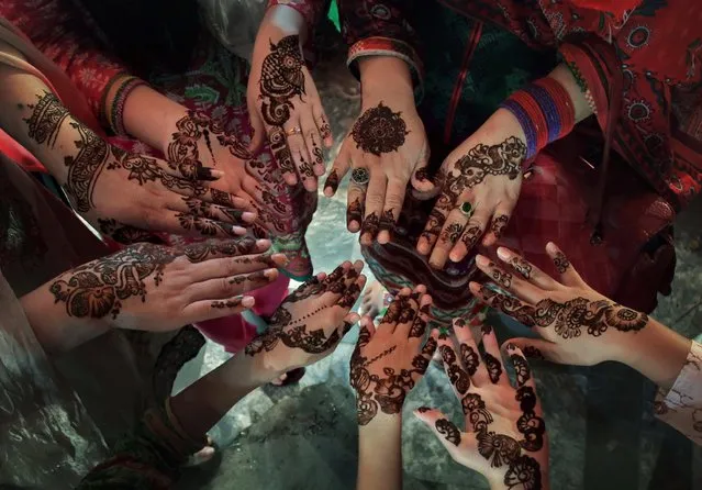 Women in a Pakistani family display their hands decorated with traditional henna in preparation for the upcoming upcoming Eid al Fitr holiday marking the end of the Muslim fasting month of Ramadan, at a market in Islamabad, Pakistan, Monday, July 4, 2016. (Photo by Anjum Naveed/AP Photo)