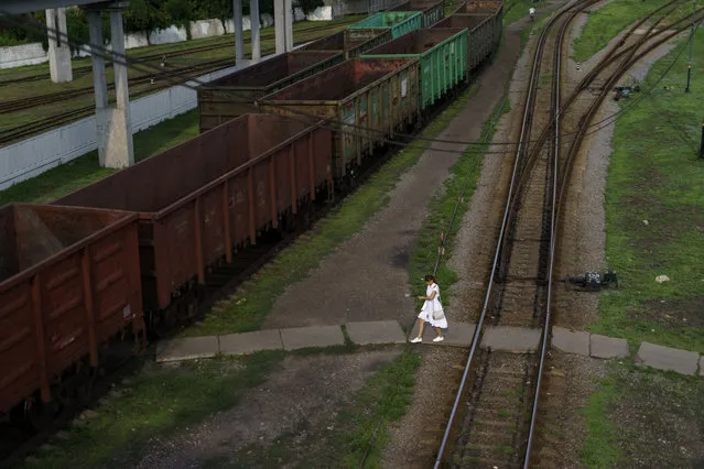 A woman crosses train tracks to get to a residential area of town in Pokrovsk, Donetsk region, eastern Ukraine, Thursday, August 11, 2022. (Photo by David Goldman/AP Photo)