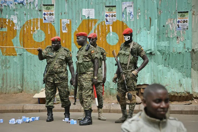 Ugandan military police, one wearing a balaclava with a skull painted on, patrol where supporters of pop star-turned-lawmaker Kyagulanyi Ssentamu, also known as Bobi Wine gather, in the Kisekka Market area of Kampala, Uganda Thursday, August 23, 2018. Bobi Wine, who opposes the longtime president Yoweri Museveni, was charged with treason in a civilian court in Gulu on Thursday, minutes after a military court dropped weapons charges. (Photo by Ronald Kabuubi/AP Photo)