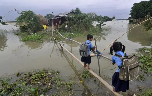 Indian schoolchildren use a bamboo bridge to cross floodwaters in Morkata village in the Morigoan district of Assam on August 25, 2014. Floods and landslides in Nepal and India have killed nearly 200 people and scores more are missing. Hundreds die every year in floods and landslides during the monsoon season in South Asia. (Photo by Biju Boro/AFP Photo)
