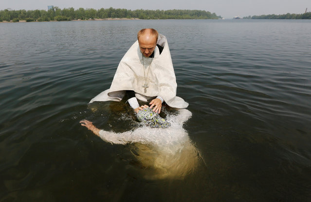 An orthodox priest baptises a woman in the Yenisei river during a ceremony marking the Christianisation of the country, which was known as Kievan Rus' at the time, by its grand prince, Vladimir I (Vladimir the Great) in 988AD, in Krasnoyarsk, Siberia, Russia July 28, 2016. (Photo by Ilya Naymushin/Reuters)
