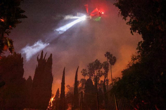 A helicopter flies, as smoke and flames rise from the Sunset Fire in the hills overlooking the Hollywood neighborhood of Los Angeles, California, U.S. January 8, 2025. (Photo by David Swanson/Reuters)