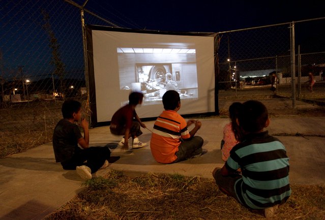 Children watch a movie projected by the Cinecleta, Moviebike, at a park in Saltillo, Mexico, September 6, 2015. (Photo by Daniel Becerril/Reuters)