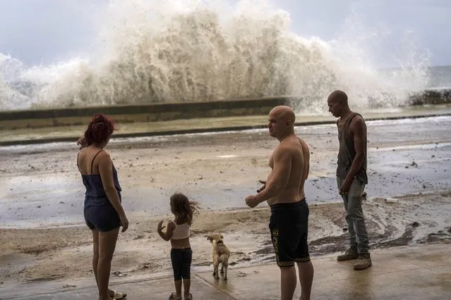 People stand along a waterfront as huge waves crash against a seawall in the wake of Hurricane Ian in Havana, Cuba, Wednesday, September 28, 2022. Cuba remained in the dark early Wednesday after Ian knocked out its power grid and devastated some of the country's most important tobacco farms when it hit the island's western tip as a major storm. (Photo by Ramon Espinosa/AP Photo)