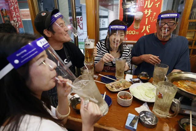 People wearing face shield, eat together at a pub in Osaka, western Japan Monday, May 25, 2020 as Japan has lifted the coronavirus state of emergency in Osaka and the two neighboring prefectures of Kyoto and Hyogo. (Photo by Suo Takekuma/Kyodo News via AP Photo)