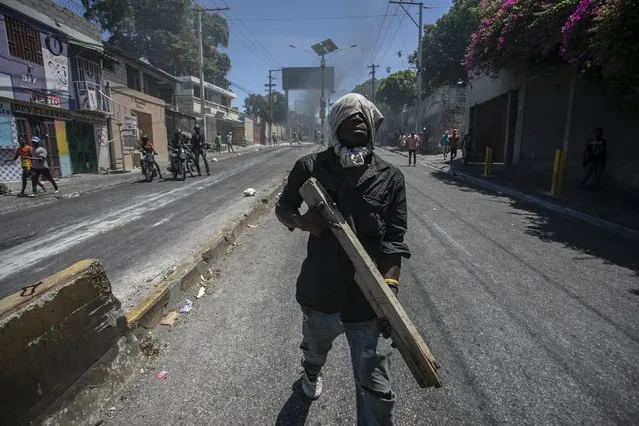 A protester carries a piece of wood simulating a weapon during a protest against fuel price hikes and to demand that Haitian Prime Minister Ariel Henry step down, in Port-au-Prince, Haiti, Thursday, September 15, 2022. (Photo by Joseph Odelyn/AP Photo)