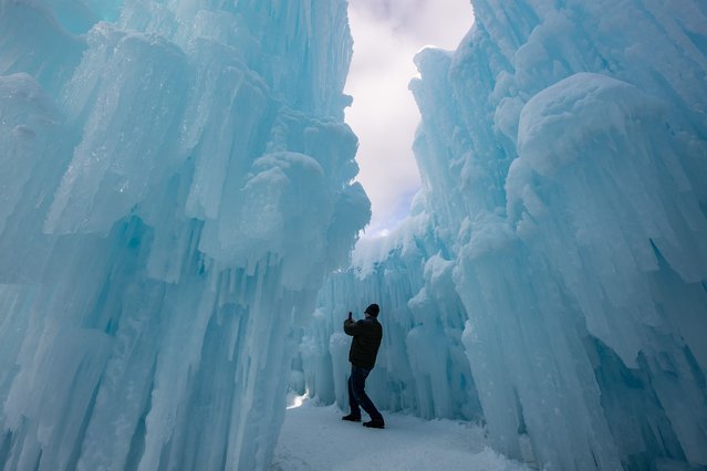 A person treks through the caverns and snow at Ice Castles in North Woodstock, New Hampshire on February 8, 2025. Founder Brent Christensen, crafted his first icy creation in the front yard of his home to bring happiness and joy to his children. Since 2011, Ice Castles has been dedicated to creating a world of ice caves, frozen waterfalls, and glaciers formed into archways, caverns, slides, and tunnels. (Photo by Joseph Prezioso/AFP Photo)