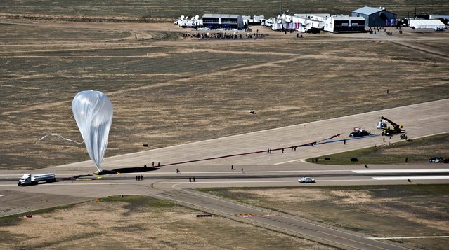 The  55-story, ultra-thin helium balloon that was to carry Baumgartner to his 24-mile free fall twists in the wind on October 9, 2012.  A 25 mph gust of wind rushed so fast that it spun the still-inflating balloon as if it was a giant plastic grocery bag, and the jump was postponed. (Photo by Predrag Vuckovic/Red Bull Stratos)