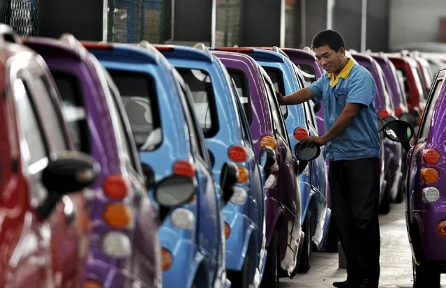 An employee checks newly-assembled electric cars at an electric vehicle factory in Zouping county, Shandong province, in this September 24, 2013 file photo. China's auto sales could be heading for a rare fall this year, but one bright spot is in so-called green cars, where sales have almost quadrupled so far in 2015. (Photo by Reuters/China Daily)