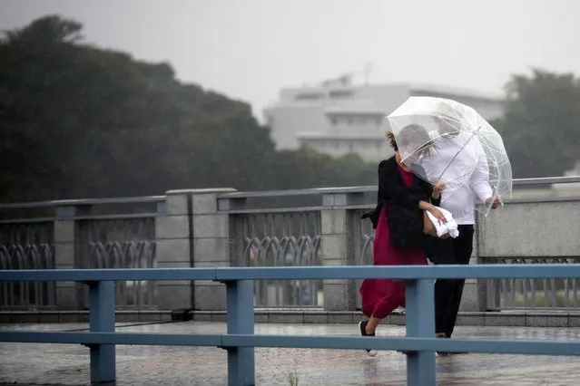 People share an umbrella against strong wind and rain as they walk on a bridge Tuesday, September 20, 2022, in Kawasaki, near Tokyo. (Photo by Eugene Hoshiko/AP Photo)