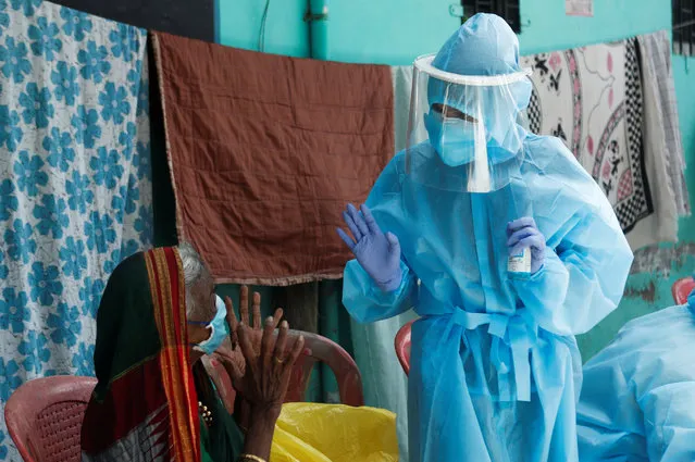 A healthcare worker wearing personal protective equipment (PPE) speaks to a resident about the coronavirus disease (COVID-19) at a check up camp in Dharavi, one of Asia's largest slums, Mumbai, India, June 7, 2020. (Photo by Francis Mascarenhas/Reuters)