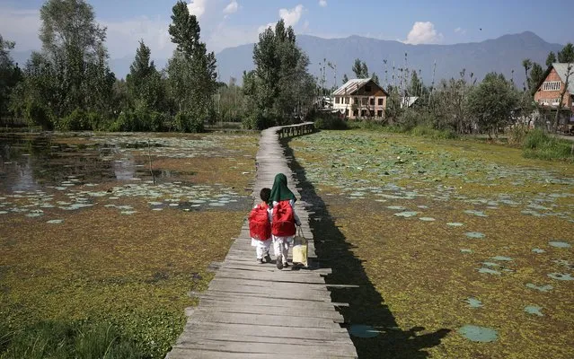 Kashmiri Muslim girl children return home from school as they walk over a wooden bridge over the murky waters of the interiors of Dal Lake on the outskirts of Srinagar, the summer capital of Indian Kashmir, 14 September 2015. (Photo by Farooq KhanEPA)