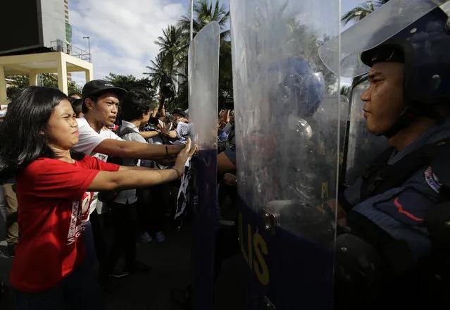 Riot police push back students protesting visiting U.S. President Donald Trump outside the ASEAN summit venue Saturday, November 11, 2017, in Manila, Philippines. Trump is currently on a visit to Asia with the Philippines as his last stop for the ASEAN leaders' summit and related summits between the regional grouping and its Dialogue Partners. (Photo by Aaron Favila/AP Photo)