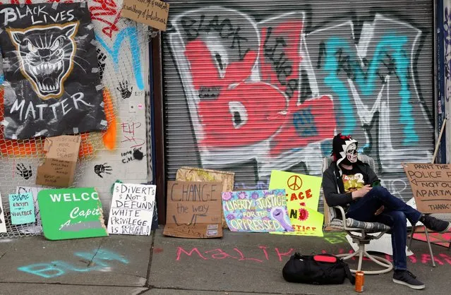 A demonstrator sits at the self-proclaimed Capitol Hill Autonomous Zone (CHAZ) during a protest against racial inequality and call for defunding of Seattle police, in Seattle, Washington, U.S. June 15, 2020. (Photo by Goran Tomasevic/Reuters)