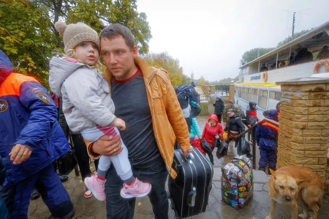 Civilians evacuated from the Russian-controlled city of Kherson walk from a ferry to board a bus heading to Crimea, in the town of Oleshky, Kherson region, Russian-controlled Ukraine on October 23, 2022. (Photo by Alexander Ermochenko/Reuters)