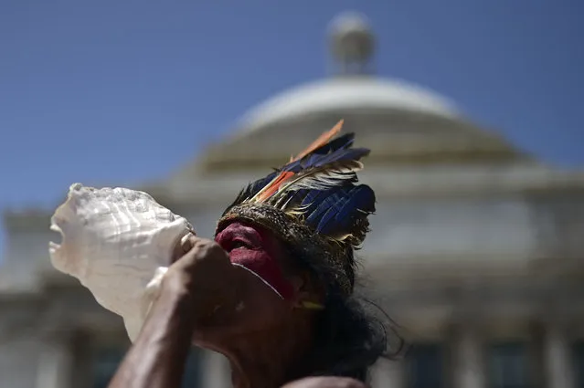 Baracutey blows on a conch shell outside the Capitol building while joining a group of activists demanding statues and street names commemorating symbols of colonial oppression be removed, in San Juan, Puerto Rico, Saturday, July 11, 2020.  Dozens of activists marched through the historic part of Puerto Rico’s capital on Saturday to demand that the U.S. territory’s government start by removing statues, including those of explorer Christopher Columbus. (Photo by Carlos Giusti/AP Photo)