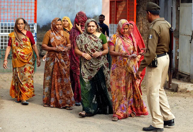 A policeman checks identity papers of women as they arrive to cast their votes at a polling station during the first phase of Gujarat state assembly election in Panshina village of Surendranagar district December 9, 2017. (Photo by Amit Dave/Reuters)