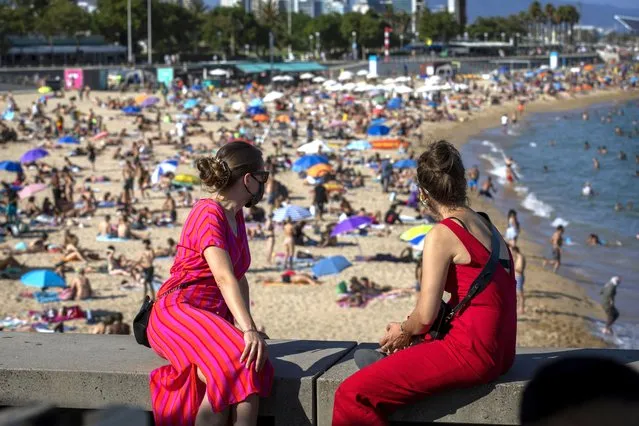 Two women look at the beach in Barcelona, Spain, Saturday, July 18, 2020. Police in Barcelona are closing access to a large area of the city's beaches due to the excess of sunbathers who decided to ignore the urgings of authorities to stay at home amid a resurgence of the coronavirus. (Photo by Emilio Morenatti/AP Photo)