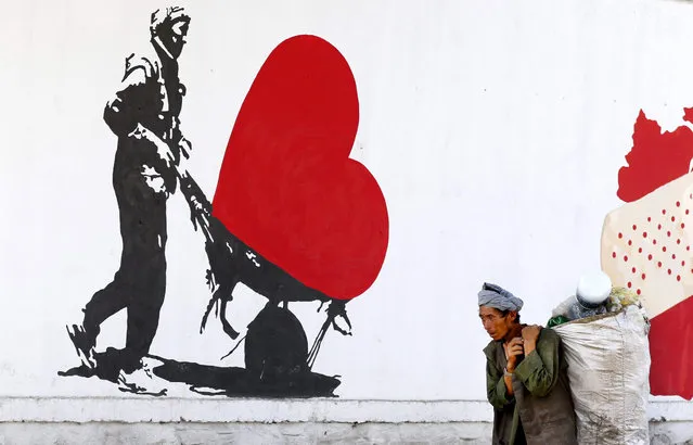 An Afghan passes by a mural on a barrier wall of the presidential palace in Kabul, Afghanistan, 18 August 2015. Mokamel and a group of artists wants to bring color into the grey streets of Kabul. (Photo by Hedayatullah Amid/EPA)