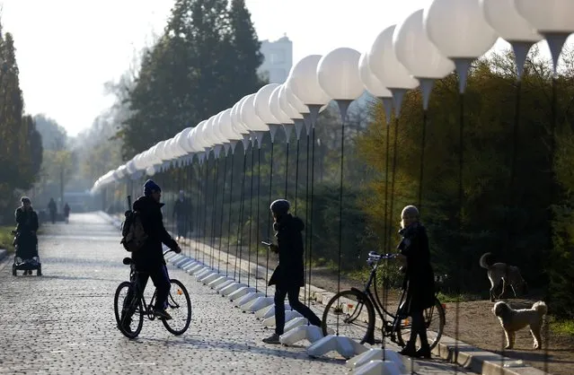 People walk under stands with balloons placed along the former Berlin Wall location at Mauerpark, which will be used in the installation “Lichtgrenze” (Border of Light) in Berlin November 7, 2014. (Photo by Pawel Kopczynski/Reuters)