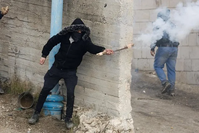 A Palestinian demonstrator releases a firecracker during clashes with Israeli forces following the funeral of Mufeed Iklayel, near Hebron in the Israeli-occupied West Bank on November 29, 2022. (Photo by Mussa Qawasma/Reuters)