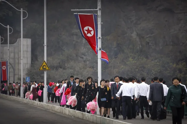 North Koreans carry decorative flowers to be used during upcoming anniversary celebrations, Thursday, October 8, 2015, in Pyongyang, North Korea. (Photo by Wong Maye-E/AP Photo)