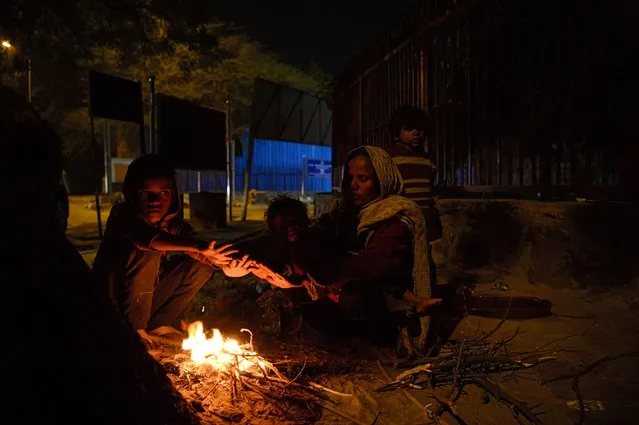 An Indian family warms up around a fire along a roadside in New Delhi on January 8, 2018. (Photo by Sajjad Hussain/AFP Photo)