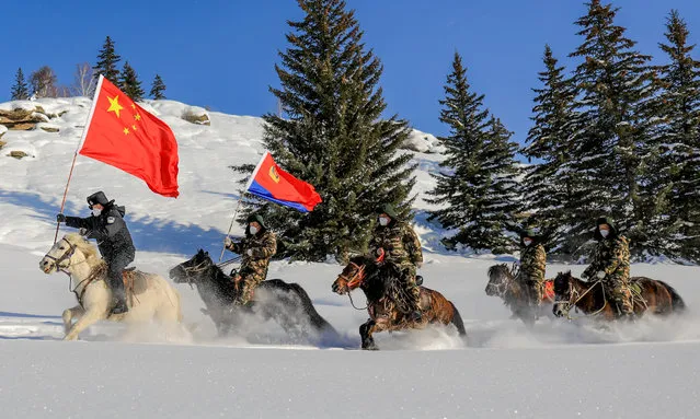 Police officers and border guards hold flags during a border patrol in Altay, Xinjiang province, China, December 30, 2022. (Photo by CFOTO/Future Publishing via Getty Images)
