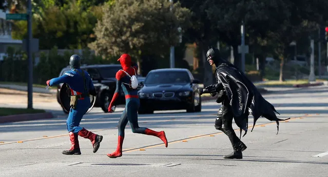 People dressed like comic book characters Captain America, Spider-Man and Batman run across the street in Pasadena, California U.S., August 27, 2016. (Photo by Mario Anzuoni/Reuters)