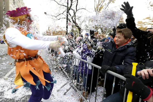 A performer, left, throws confetti on a crowd during the Macy's Thanksgiving Day Parade, Thursday, November 27, 2014, in New York. (Photo by Julio Cortez/AP Photo)