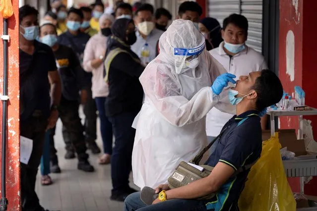 A doctor collects a sample for a coronavirus test outside a clinic in Kajang on the outskirts of Kuala Lumpur, Malaysia, Friday, October 23, 2020. Malaysia restricted movements in its biggest city Kuala Lumpur, neighbouring Selangor state and the administrative capital of Putrajaya from Wednesday in an attempt to curb a sharp rise in coronavirus cases. (Photo by Vincent Thian/AP Photo)