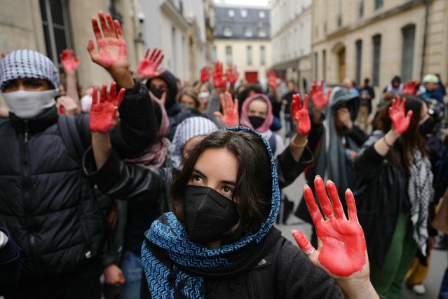 Protesters display mock blood on their hands as they take part in a demonstration in front of the Institute of Political Studies (Sciences Po Paris) occupied by students, in support of Palestinians, in Paris on April 26, 2024. A few dozen students stay mobilized in support of Palestinians occupying a new building at Sciences Po Paris since April 25, 2024, evening, the day after police evacuated another of the school's sites, in the wake of actions at American universities. (Photo by Dimitar Dilkoff/AFP Photo)