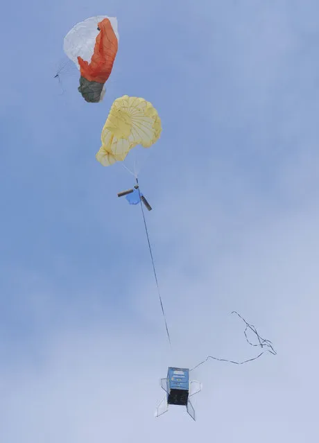 Parachutes slow down the descent of a 10-foot, 450 pound porta-potty, mounted on rocket motors, Saturday, December 6, 2014, during rocket launches by Michiana Rocketry in a field in Three Oaks, Mich. (Photo by Don Campbell/AP Photo/The Herald-Palladium)