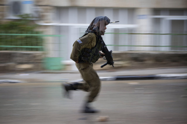 An Israeli soldier runs during clashes with Palestinian demonstratorsi n Al Bireh, neighboring the Israeli settlement of Psagot, near the West Bank city of Ramallah, Friday, November 6, 2015. (Photo by Majdi Mohammed/AP Photo)