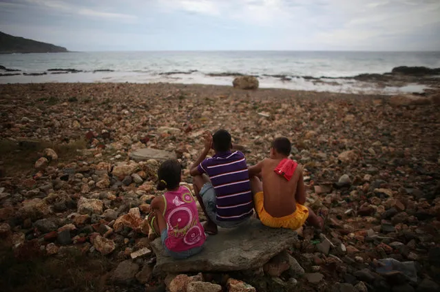 Children watch waves splashing on the beach at Siboney ahead of the arrival of Hurricane Matthew in Cuba, October 4, 2016. (Photo by Alexandre Meneghini/Reuters)