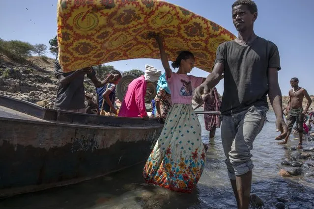 Tigray refugees who fled the conflict in the Ethiopia's Tigray region carry their belongings off a boat after arriving on the banks of the Tekeze River on the Sudan-Ethiopia border, in Hamdayet, eastern Sudan, Saturday, November 21, 2020. The U.N. refugee agency says Ethiopia's growing conflict has resulted in thousands fleeing from the Tigray region into Sudan as fighting spilled beyond Ethiopia's borders and threatened to inflame the Horn of Africa region. (Photo by Nariman El-Mofty/AP Photo)