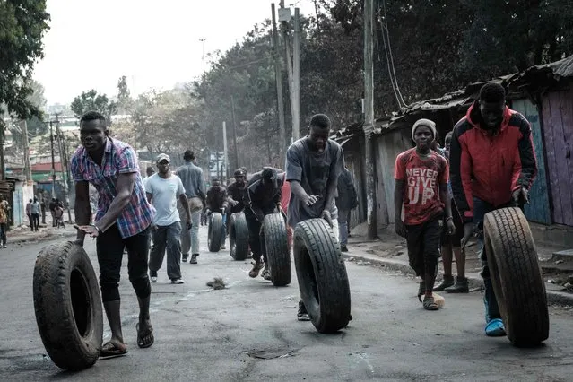 Protesters roll tyres towards a barricade in Kibera, Nairobi, on March 30, 2023 during a protest called by the opposiion coallition “Azimio la Umoja”. Kenyan police again clashed with hundreds of protesters on Thursday as a third round of demonstrations against the government and high food prices raised fears of further violence. Opposition leader Raila Odinga has called for regular protests every Monday and Thursday, accusing President William Ruto of stealing last year's election and of failing to control the surging cost of living. (Photo by Yasuyoshi Chiba/AFP Photo)
