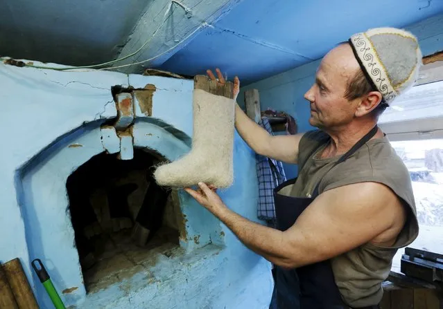 Ivan Plakhuta, 54, the owner of a small workshop manufacturing valenki, Russian traditional footwear, inspects a valenok before putting it into a dryer in the remote Siberian village of Bolshaya Rechka, located in Taiga area in the foothills of the Western Sayan Mountain Ridge in the Yermakovsky district of Krasnoyarsk region, Russia, November 10, 2015. (Photo by Ilya Naymushin/Reuters)